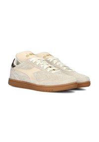 Beige suède sneakers met crème accenten, witte veters en een gumrubberen zool. Kenmerkt zich door een ronde neus en een gladde hakkap.