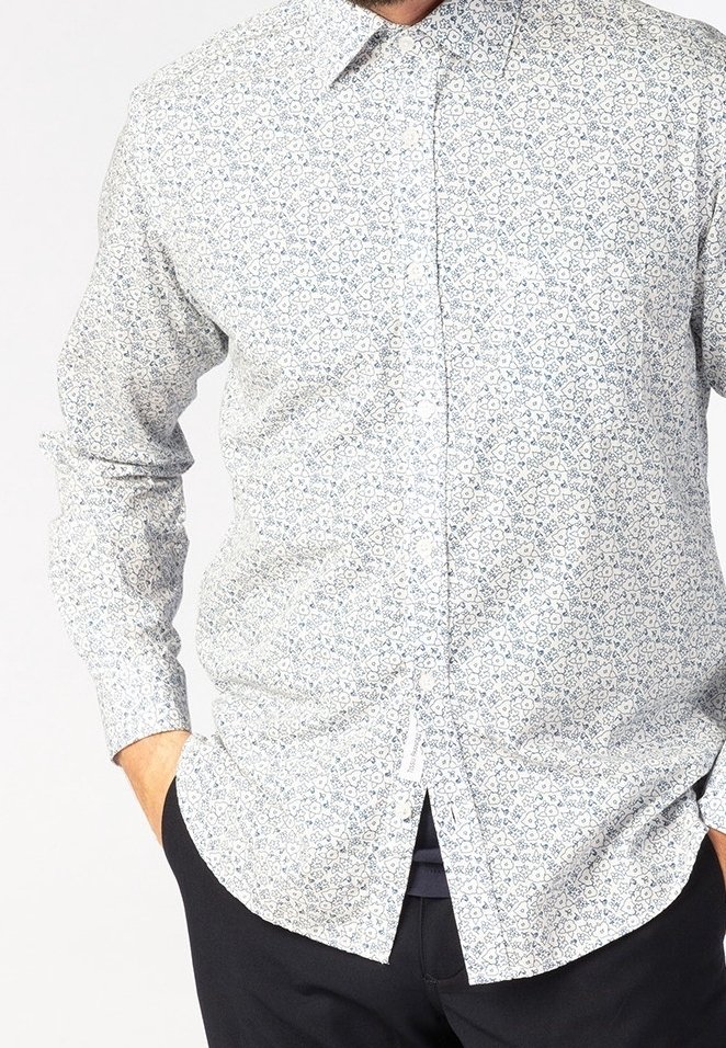 Biała koszula z guzikami z niebieskim kwiatowym wzorem. Długie rękawy i klasyczny kołnierzyk. Materiał wydaje się lekki i gładki w dotyku.