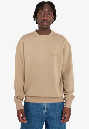 Sudadera beige con cuello redondo, puños y dobladillo acanalados, y un sutil logo bordado de "Element" en la parte delantera. Combinada con jeans azules.