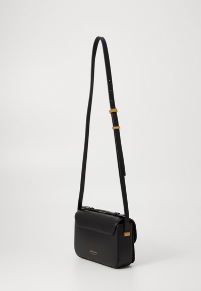 Borsa a tracolla in pelle nera con forma rettangolare, tracolla regolabile, dettagli in oro e chiusura a patta. Texture liscia, design minimal.