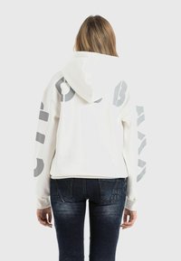 White cropped hoodie with a drawstring hood, featuring large gray text on the back and sleeves. Soft fabric with ribbed cuffs and hem.