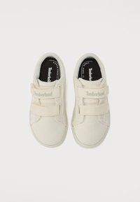 Valged kangast tossud Velcro rihmadega, ümar nina, pehmendada krae ja must sisu, millel on Timberlandi logo. Lamedad tallad.