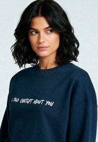 Navy plavi dukserica izrađena od mekog materijala, s okruglim izrezom i vidljivim šavovima, s bijelim natpisom "REKAO SAM CHATGPT-U O TEBI."