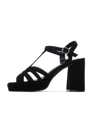 Sandalo con tacco alto in suede nero con ampie fasce, design a T-bar, fibbia regolabile alla caviglia e tacco a blocco per la stabilità. Texture liscia.
