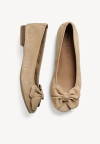 Bailarinas de ante beige con punta redondeada y un lazo decorativo en la parte delantera. El bajo tacón de madera añade una elevación sutil.