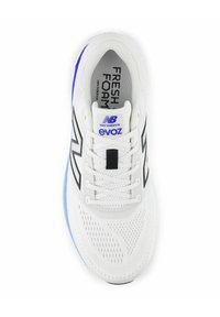Zapatilla de running blanca con parte superior de malla transpirable, detalles de diseño en negro, marca "Fresh Foam" y suela de color azul claro. Presenta cordones tradicionales.