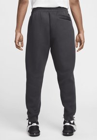 Mörkgrå sweatpants med elastisk midja, sidoficka, avsmalnande ben och ribbade muddar, tillverkade av mjukt, texturerat material.