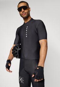 Schwarzer Radsportanzug mit Reißverschluss vorne, kurzen Ärmeln und strukturierten Akzenten. Zubehör umfasst schwarze Sonnenbrillen und einen schwarzen Helm.