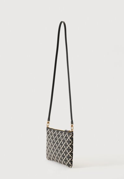 Sac bandoulière noir avec motif croisé blanc, fermeture éclair dorée et une longue fine sangle noire suspendue sur un fond clair uni.