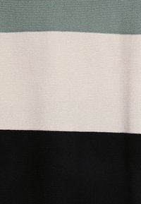 Tkanina w paski z trzema poziomymi pasami: jasna zieleń, kremowy i czarny. Teksturowany dzianinowy materiał o prążkowanej powierzchni.