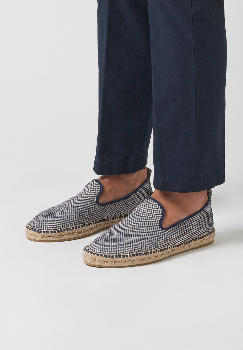 Espadrilles slip-on marine et beige avec un motif tissé, semelle en jute et un design découpé sur les côtés pour la respirabilité.