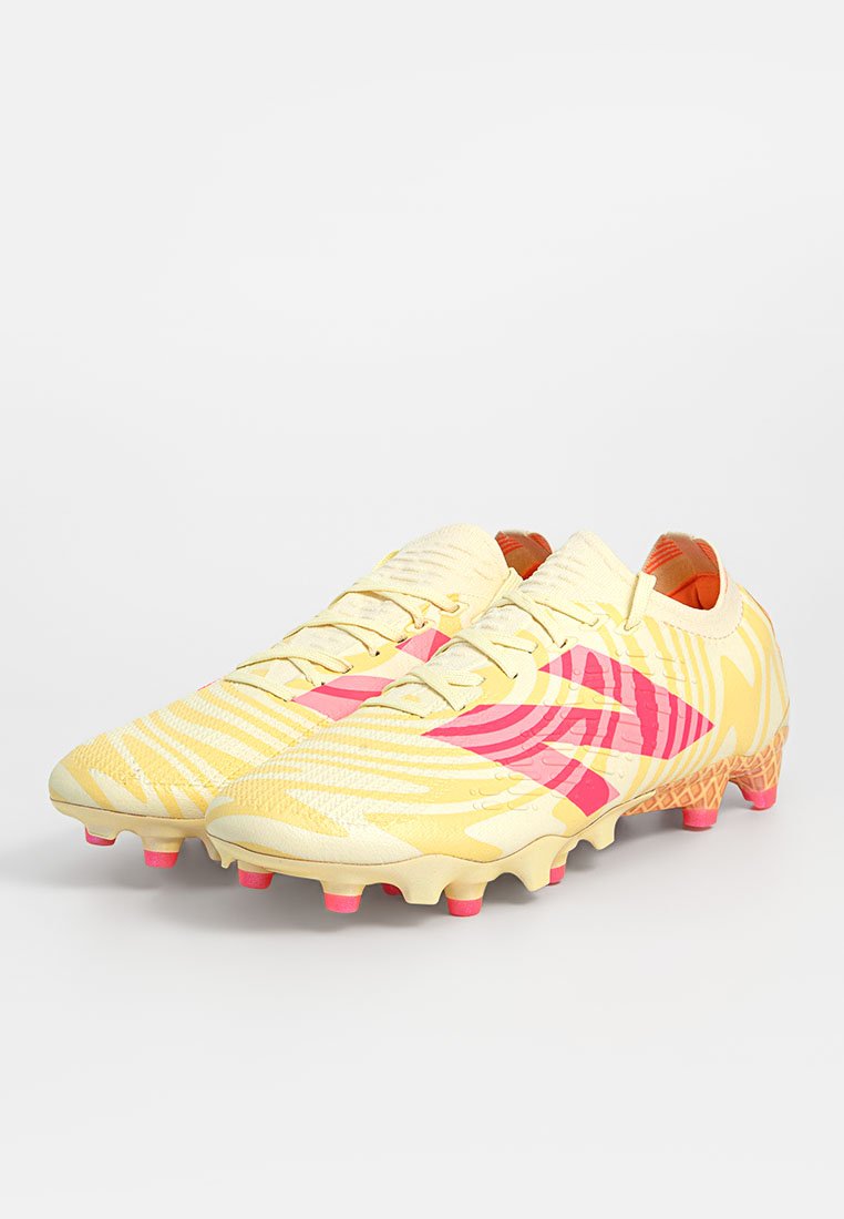 Geel voetbal schoenen met roze accenten, een getextureerd patroon en een gevormde zool met meerdere noppen voor grip. Lichtgewicht synthetisch materiaal.
