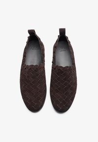 Braune Wildleder- Slipper zeichnen sich durch ein geflochtenes Design und eine abgerundete Zehenpartie aus. Die Schuhe verfügen über ein glattes Innenfutter und eine kleine Zuglasche hinten.