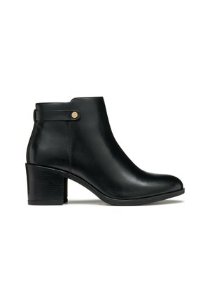 Stivale ankle in pelle nera con punta arrotondata, tacco a blocco e una cintura laterale con un'acca dorata. Texture liscia, design elegante.