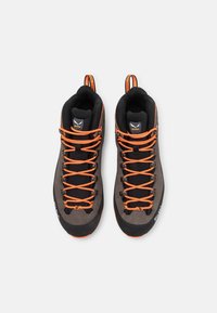 Scarpe da trekking grigie con dettagli neri, dotate di lacci arancioni, design alto e superficie texturizzata per una migliore aderenza.