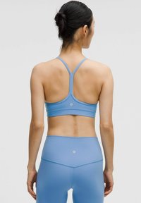 Zila sporta krūšturis ar racerback dizainu, izgatavots no elastīga materiāla. Viegla tekstūra ar maigu logo detaļu uz joslas.