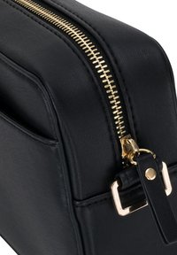 Schwarze Lederhandtasche mit einem goldenen Reißverschluss und Hardware, rechteckige Form, glatte Textur und dezente Nahtdetails entlang der Kanten.