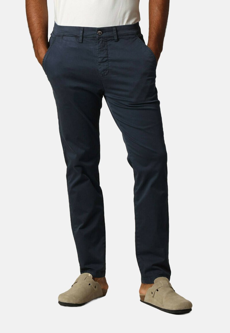 Chinos navy en tissu léger avec un devant plat, fermeture à bouton et poches latérales ; associés à des chaussures beiges à enfiler.