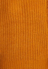 Pull en tricot de couleur orange vif, présentant un motif texturé en côtes avec une finition lisse et des coutures régulières tout au long.