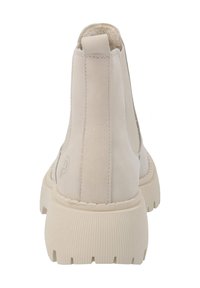 Botines de tobillo beige claro, hechos de cuero suave, con una suela de goma texturizada y paneles laterales elásticos para facilitar su uso, que presentan un detalle de logo.
