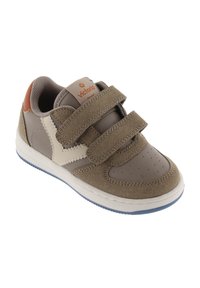 Bruine sneaker met beige accenten, klittenbandsluitingen, geperforeerde neus en gestructureerde suède en leren materialen. Duurzame rubberen buitenzool met grip.