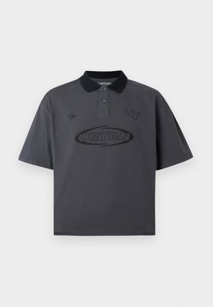 Σκούρο γκρι πόλο μπλουζάκι με μαύρο γιακά, δύο κουμπιά και μαύρα γραφικά κείμενα και σύμβολα στο μπροστινό μέρος, παρουσιάζεται σε λευκό φόντο.