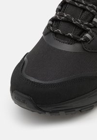 Pantofle de sport negre cu un superior din țesătură texturată, design fără cusături, talpă din cauciuc și vârf întărit pentru durabilitate.