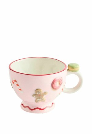 Pink ceramic cup decorated with a gingerbread man, donut, candy cane, and scalloped red trim, with a round handle topped by a green macaron.