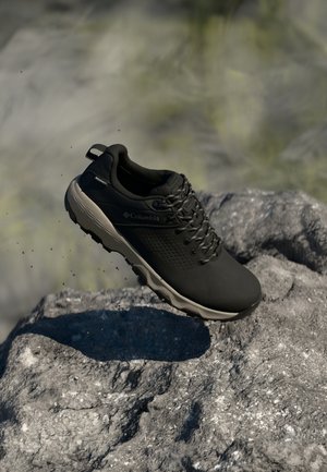 Czarne buty sportowe z siateczkowym wierzchem, teksturowaną powierzchnią i gumową podeszwą; charakteryzują się niskim profilem i wzmocnionym noskiem.