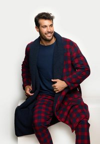 Roter und marineblauer karierter Bademantel mit einem flauschigen marineblauen Kragen, kombiniert mit einem dunkelblauen Oberteil, das einen lockeren Schnitt und lange Ärmel hat.