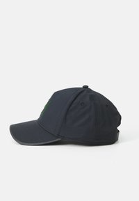 Casquette de baseball marine avec une visière incurvée, dotée d'un logo vert à l'avant, fabriquée en tissu à la texture lisse, avec une sangle ajustable à l'arrière.
