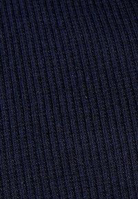 Tejido acanalado de un azul marino oscuro con una superficie texturizada que presenta líneas verticales, creando un patrón uniforme en el material.