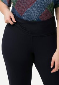 Leggings negros con una cinturilla ancha y suave. El material es liso y elástico, diseñado para la comodidad y la facilidad de movimiento.