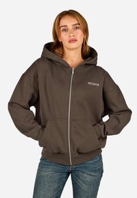 Sötétbarna zipzáras kapucnis felső tágas kapucnival, elülső zsebekkel és 'PEGADOR' hímzett részlettel. Puha anyagból készült, bordás mandzsettákkal.