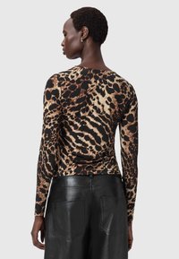 Garšas piedurkņu krekls ar leopardu rakstu brūnā un krēmkrāsā uz melna fona, izgatavots no mīksta, elastīga auduma. Stilizēts ar apaļu kakla izgriezumu.