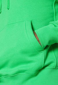 Ljusa gröna hoodie gjord av mjukt tyg; har en känguruficka, ribbade muddar och en huva med dragsnöre. Enkel design och livfull färg.