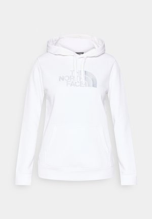 Bijela majica s kapuljačom od mekog materijala s prednjim džepom. Ima srebrni logo i zakrivljeni grafički motiv na prsima. Kapuljača s vezicama i rebrasti rubovi na rukavima.