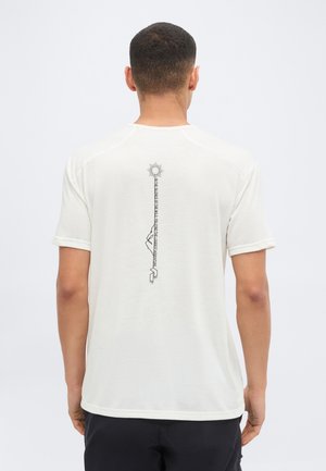 Homme de dos portant un t-shirt blanc avec un graphisme vertical noir représentant un soleil, une montagne et une forme géométrique sur le haut du dos.