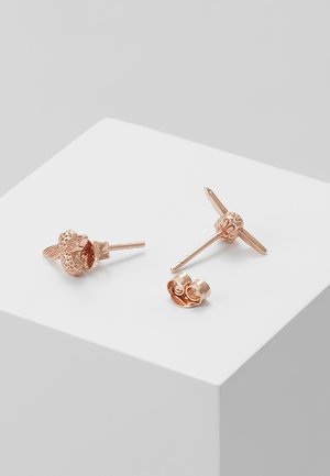 Różowo-złote kolczyki w kształcie pszczółek z detalicznymi skrzydłami i fakturowanymi ciałami, prezentowane na białej powierzchni.