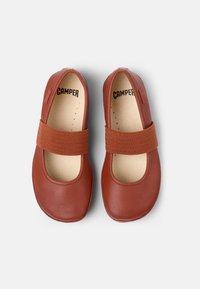 Braune Leder-Ballerinaschuhe mit elastischem Riemen, runder Spitze, glatter Textur und minimalistischem Design, ausgestattet mit einer beigen Innensohle mit Perforationen.