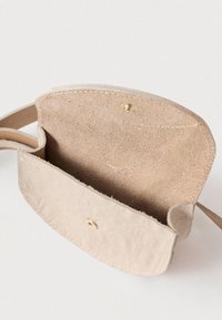 Bež kožna torba preko tijela s teksturiranim cvjetnim uzorkom, zatvaranjem na pritisak i unutrašnjošću od antilopa. Remen je pričvršćen s obe strane.