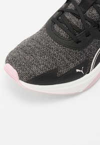 Harmaa teksturoitu urheilujalkine mustilla yksityiskohdilla, valkoisella pohjalla ja vaaleanpunaisilla yksityiskohdilla. Varustettu nauhakiinnityksellä ja erottuvalla logolla.