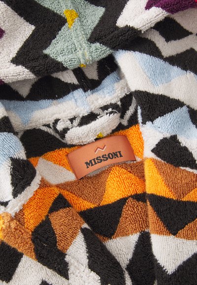 Πολύχρωμη πετσέτα φτιαγμένη από τερέ, με ζιγκ-ζαγκ σχέδια σε μαύρο, πορτοκαλί, κίτρινο, πράσινο και μπλε χρώμα. Περιλαμβάνει καφέ δερμάτινη ετικέτα με την ένδειξη "MISSONI."