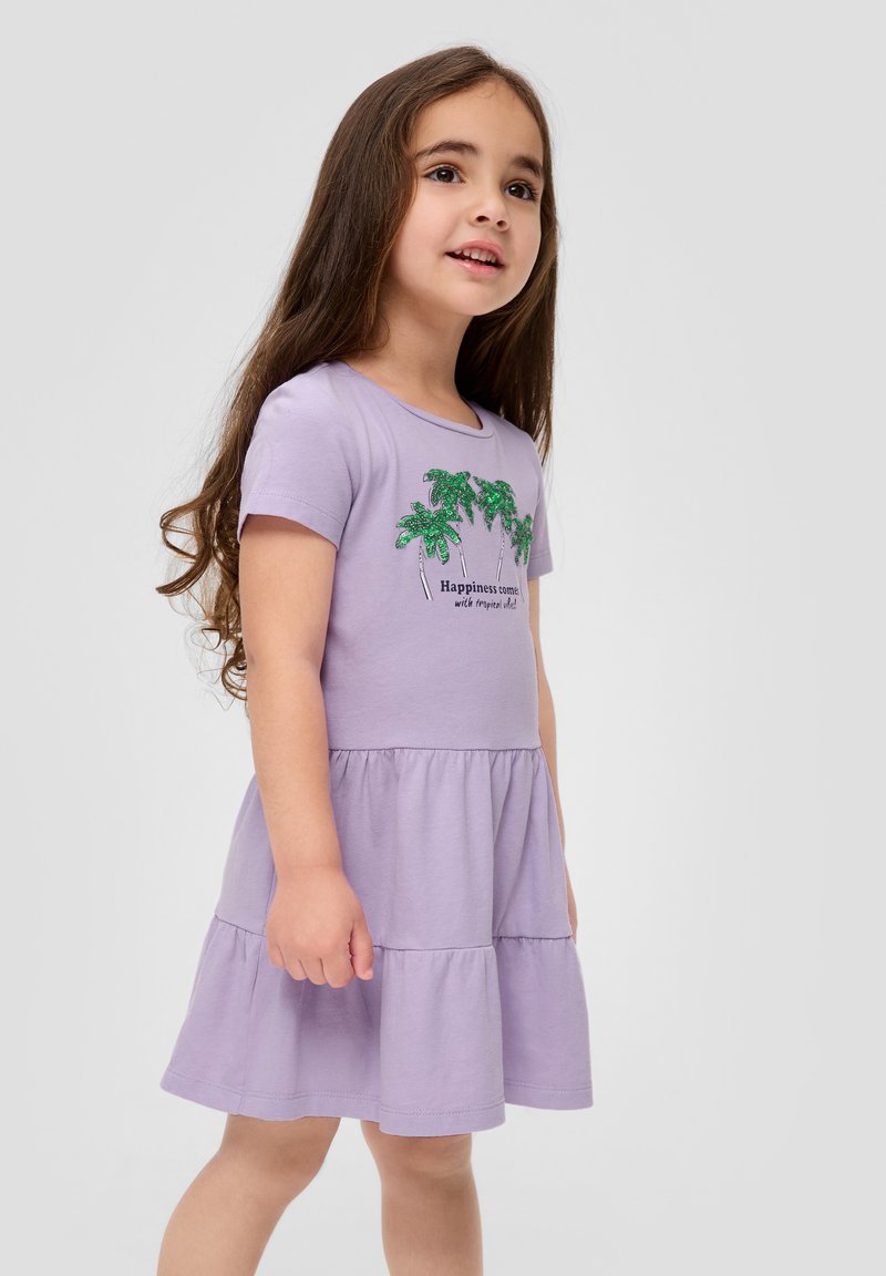 Lavendelfarbenes Kleid aus weichem Stoff mit Rundhalsausschnitt, kurzen Ärmeln und einem gestuften Rock. Grünes Palmenmuster mit schwarzem Text.