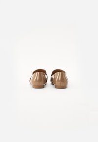 Ballerines en cuir synthétique marron avec un dos arrondi, texture lisse et design minimaliste, dotées d'un petit talon et d'un style à enfiler.