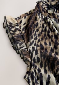 Leopard print blouse with ruffled sleeves, featuring shades of brown, black, and cream. Lightweight fabric with a soft texture.