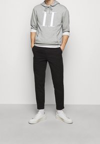 Sudadera gris con el "II" impreso en blanco, capucha con cordón, pantalones negros y zapatillas blancas. Diseño sencillo, material de algodón y ajuste relajado.