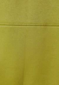 Tela verde con una textura suave, que presenta un color uniforme y un cosido preciso a lo largo de las costuras. No hay patrones ni detalles adicionales visibles.