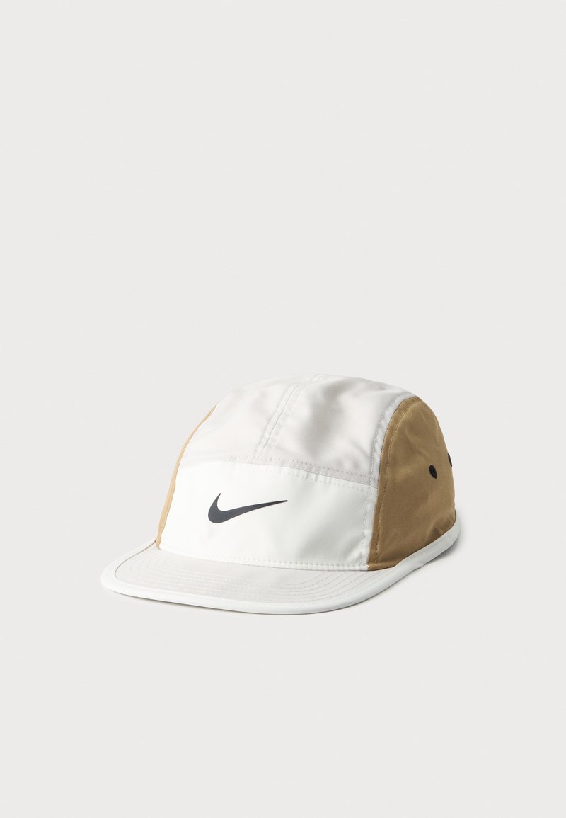 Бяла и бежова шапка на Nike с черно лого на предния панел, плоска козирка и по две черни вентилационни дупки от всяка страна.