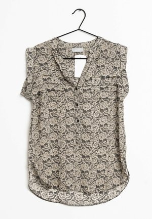 Top senza maniche con motivo in beige e nero. Presenta una scollatura a V, bottoni frontali e un orlo arrotondato. Il tessuto ha un design floreale.